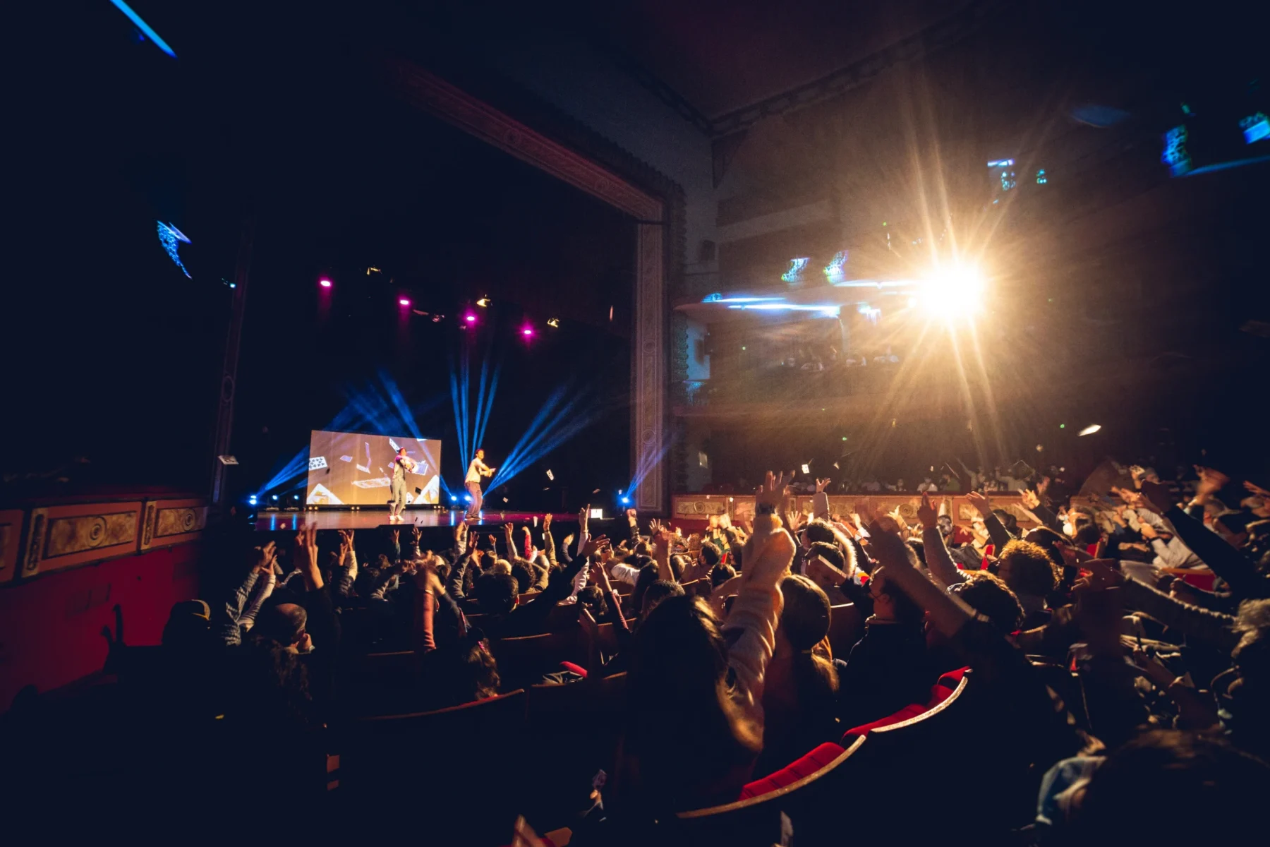 Teatro lleno con el público levantando las manos